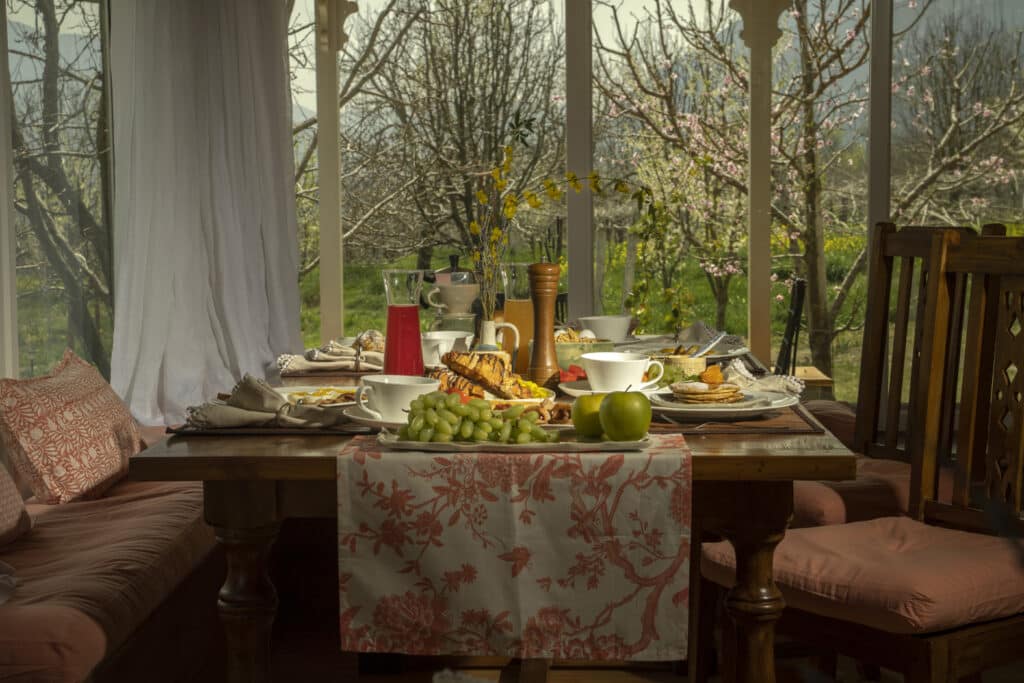 A beautifully set breakfast table with fresh fruits, pastries, juice and coffee