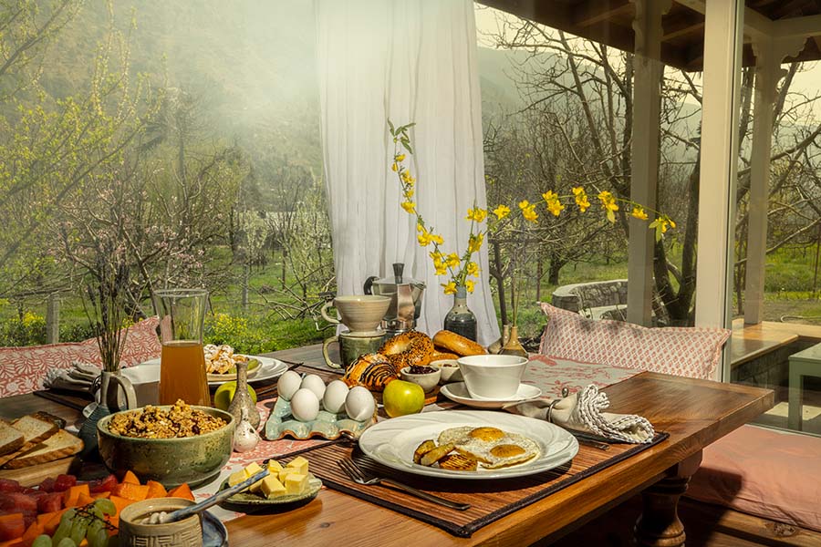 A beautifully set breakfast table with fresh fruits, pastries, juice and coffee